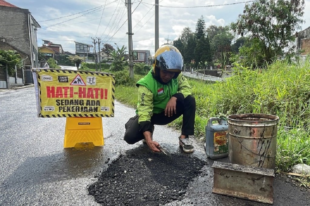Viral Aksi Ojol di Bandung Tambal Jalan Berlubang Pakai Uang Pribadi Hasil Narik