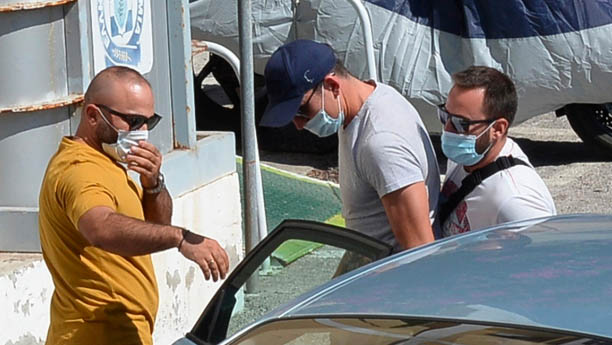 Dengan tangan diborgol, kapten Manchester United Harry Maguire (tengah) dibawa kepolisian Yunani, Kamis (20/8/2020). (Foto: The Sun)