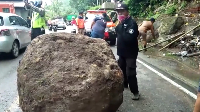 Petugas gabungan dan warga evakuasi batu besar di tengah jalan (Budi Sunandar/iNews)