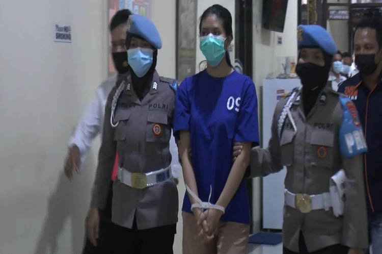 Tersangka sate beracun Na tersangka pengirim sate beracun dikawal polisi sebelum pers rilis di mapolres Bantul. (foto: iNews.id/Trisna Purwoko)