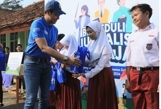 Corporate Secretary BRI Agustya Hendy Bernadi menyerahkan bingkisan kepada perwakilan siswa SDN Gunung Geulis 01 dan 02. (Foto: BRI)