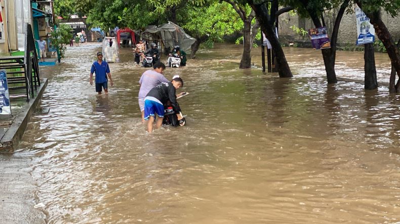 Warga ikut mendorong sepeda motor warga yang mogok akibat banjir di Bintara, Bekasi , Sabtu (6/7/2024) (Foto: Danandaya Arya)