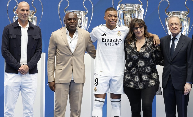 Pemain baru Real Madrid Kylian Mbappe berfoto bersama Presiden Real Madrid Florentino Perez (kanan), Zinedine Zidane (kiri), ayahnya Wilfried Mbappe dan ibunya Fayza Lamari, di Santiago Bernabeu, Selasa (16/7/2024). (Foto: EPA-EFE/CHEMA MOYA)