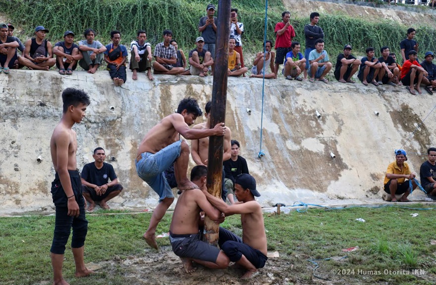 Pekerja konstruksi IKN tampak mengikuti lomba panjat pinang. (Foto: Humas Otorita IKN)