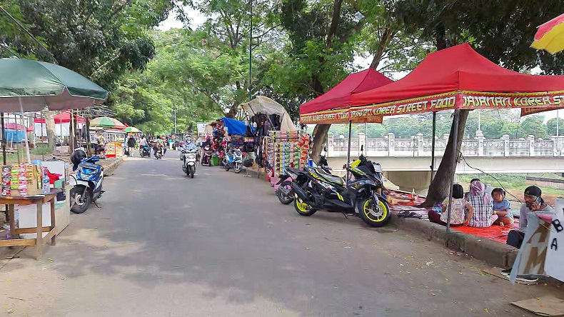 Libur Akhir Pekan, Warga Berpiknik Santai di Pinggir Banjir Kanal Timur