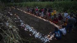 Warga Menyalakan Lilin di Atas Pemakaman Massal Korban Banjir Bandang NTT