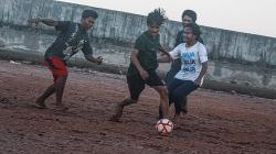 Potret Remaja Bermain Sepak Bola di Pinggir Tanggul Muara Baru