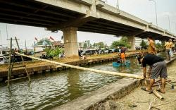 Kompaknya Warga Persiapkan Lomba Panjat Pinang di Aliran Sungai Kalimalang