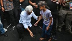  Momen Ganjar Bantu Perbaiki Sandal Jepit Anak Kecil yang Terlepas di Tengah Ribuan Warga<