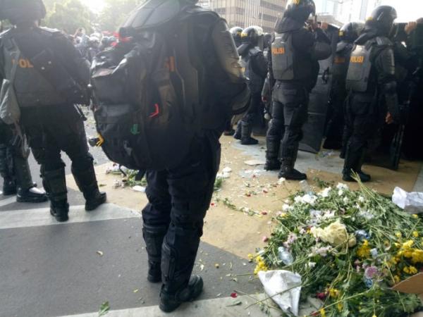 Massa pendukung Prabowo-Sandi yang berunjuk rasa di depan Bawaslu memberikan polisi bunga mawar, Selasa (21/5/2019). (Foto: iNews.id/Wildan Catra Mulia)