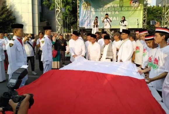 Menteri Agama (Menag) Lukman Hakim Saifuddin ikut membentangkan bendera merah putih raksasa saat parade Hari Santri di Kawasan Kementerian Agama (Kemenag), Jalan MH Thamrin, Jakarta Pusat, Minggu (13/10/2019). (Foto: Okezone/Fahreza Rizky)