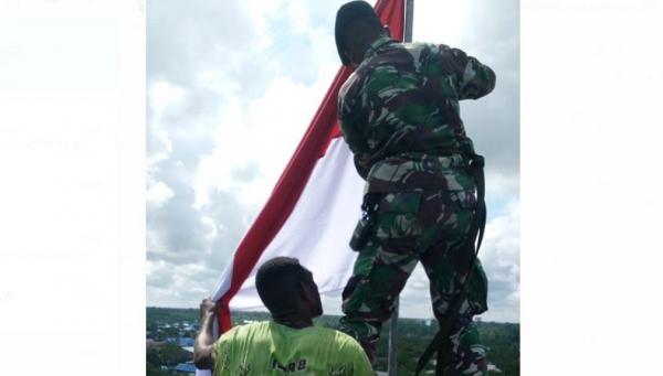 Prajurit TNI dan warga Asmat mengibarkan Bendera Merah Putih di Tower setinggi 30 meter di Asmat, Papua. (Foto: Istimewa)