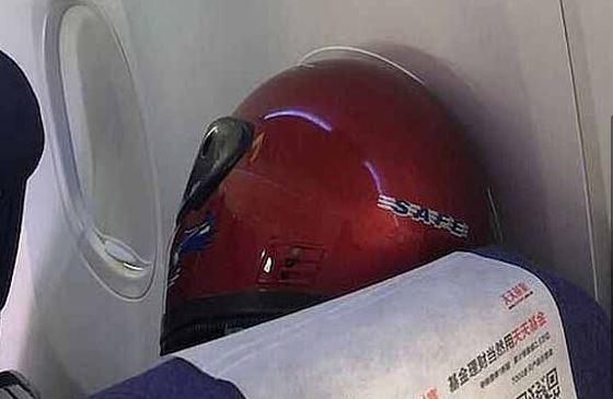 Seorang penumpang pesawat menuju Perth menggunakan helm untuk menutupi wajahnya. (FOTO: 7news)