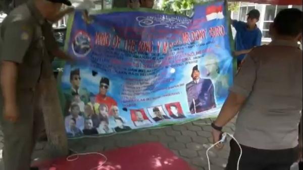 Petugas Satpol PP Tangerang dan Polres Metro Tangerang melepaskan baliho King of The King yang terpasang di depan Terminal Poris, Cipondoh, Kota Tangerang, Banten. (Foto: iNews/Hasnugara)