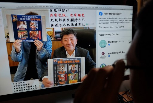 Seorang pria melihat halaman web Facebook Kementerian Luar Negeri Taiwan yang menunjukkan Menteri Kesehatan Taiwan Chen Shih-chung memegang plakat mempromosikan pencegahan virus korona di Taipei. (FOTO: Sam Yeh / AFP)