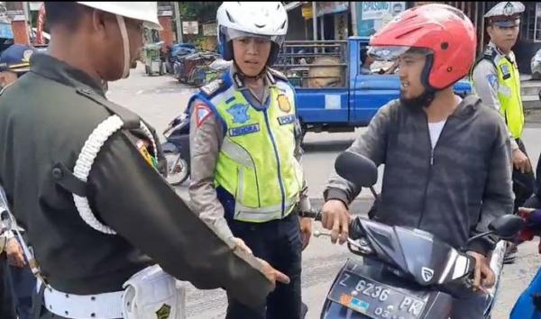 Petugas tegur warga yang pakai atribut militer Petugas tegur warga yang pakai atribut militer, Kamis (20/2/2020) (Foto: iNews/Asep Juhariyono)