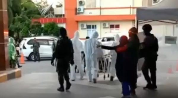 Anak korban menangis histeris dan ditenangkan petugas menolak jenazah ibunya dimakamkan sesuai protokol Covid-19. (Foto: iNews/Bugma)