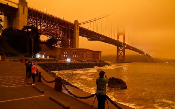 Sejumlah orang mengabadikan pemandangan langka di bawah Jembatan Golden Gate di Kota San Francisco dimana langit berubah warna menjadi orange akibat kebakaran lahan di California. (foto: CTV)