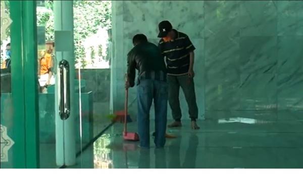 Pengurus masjid membersihkan pecahan kaca yang dirusak pelaku. (Foto iNews/Ervan David).