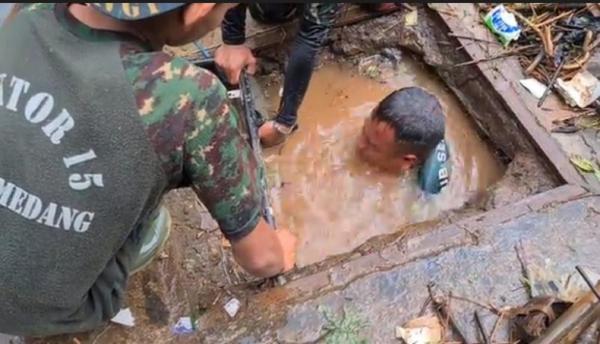 Anggota Satgas Subsektor 15 Citarum Harum, Serka Erik Krisyana menyelam di selokan, Jalan Raya Parakan Muncang, Kecamatan Cimanggung, Sumedang. (Foto iNews/Beben HVA).