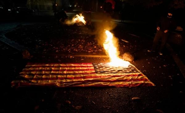 Demonstran Bakar Bendera Demonstran anti-Trump melakukan aksi pembakaran bendera Amerika Serikat dalam unjuk rasa yang berujung ricuh di Seattle, Rabu (3/11/2020) malam waktu setempat. (foto: The Sun)