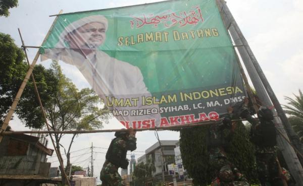 Prajurit TNI dan personel gabungan menurunkan baliho bergambar Habib Rizieq Shihab di kawasan Petamburan, Jakarta, Jumat (20/11/2020) karena dianggap menyalahi izin. (Foto: SINDOnews/Eko Purwanto)