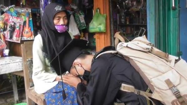 mahasiswa wisuda di makam sang ayah Mochamad Nadif Nasrulloh (23), yang baru mengikuti wisuda virtual di depan makam sang ayah bersujud di hadapan ibunya di Banjarnegara, Jateng, Selasa (24/11/2020). (Foto: iNews/Widodo)