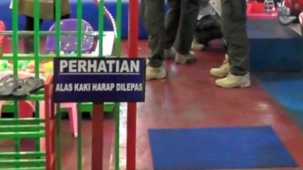 Lepas sepatu-1 Petugas gabungan prokes di Pasaman, Sumbar masuk ke area bermain anak dengan mengenakan sepatu (Wahyu Sikumbang/iNews)