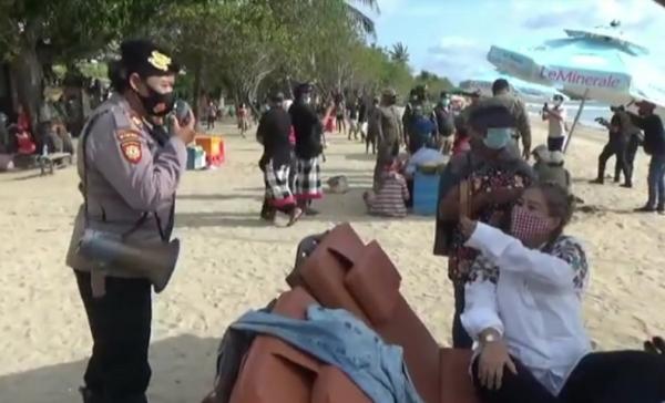 Razia pantai kuta Petugas kepolisian memberi peringatan kepada wisatawan yang belum menerapkan protokol kesehatan. (iNews.id/Bagus Alit)