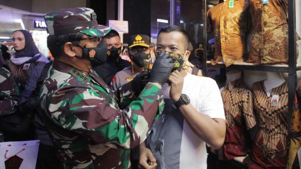 Panglima TNI Marsekal TNI Hadi Tjahjanto memakaikan masker kepada seorang anak dalam kunjungannya di Pasar Tanah Abang, Jakarta, Minggu (31/1/2021). (Foto: Puspen TNI).