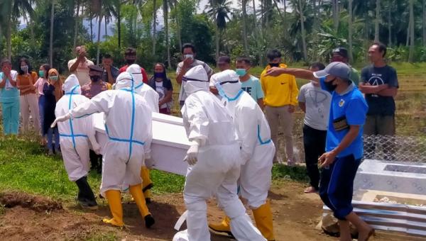 Suasana saat petugas hendak memakamkan pasien Covid-19. Empat petugas  pemakaman Covid-19 RSUD Kotamobagu dianiaya. (Foto: Okezone/Subhan Sabu)