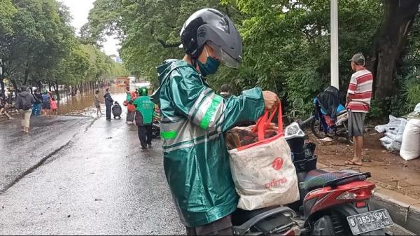 dapat ikan Salah satu warga membawa sejumlah ikan mas berukuran besar dari hasil menjala di lokasi banjir, Jalan TB Simatupang, Jakarta Selatan, Sabtu (20/2/2021). (Foto: Ari Sandita/ Sindonews).
