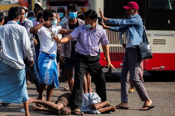 Pendukung junta militer mengacungkan senjata tajam di dekat tubuh demonstran penolak kudeta yang terkapar di Yangon, Myanmar, Kamis (25/2/2021). (Foto: Reuters)