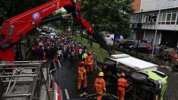 Petugas Damkar mengevakuasi sebuah truk yang terguling di Jalan Ir Soekarno Hatta (Merr), Surabaya, Jawa Timur, Kamis (25/2/2021). (Foto: SINDONews/Ali Masduki)