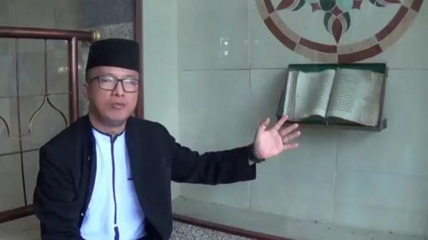 MASJID MUNGSOLKANAS1 Sekretaris DKM Dedy Priatna menunjukkan Alquran tua tulisan tangan peninggalan KH Abdurrohim atau Mama Aden pendiri Masjid Mungsolkanas. (Foto: iNews/Ervan David)