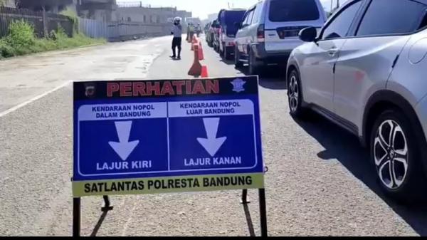 Kendaraan asal Jabodetabek mengantre untuk diperiksa petugas Satlantas Polresta Bandung yang melakukan operasi penyekatan di Km 155 Tol Cileunyi. (Foto: iNews/Mujib Prayitno)