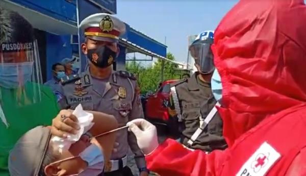 Petugas Polres Sidoarjo melakukan tes swab antigen kepada pemudik yang terjaring operasi penyekatan, Minggu (16/5/2021). (Foto: Pramono Putra)