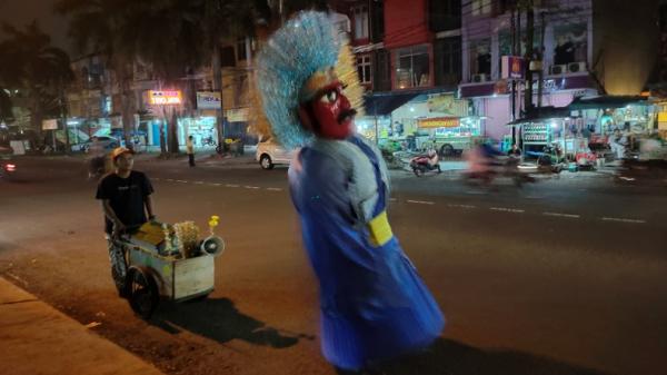 Ondel-ondel Kim Pengamen ondel-ondel mengais rezeki di Jalan Boulevard Raya, Grand Galaxy Park, Bekasi, Minggu (13/6/2021) malam. (Foto: iNews.id/Riezky Maulana)