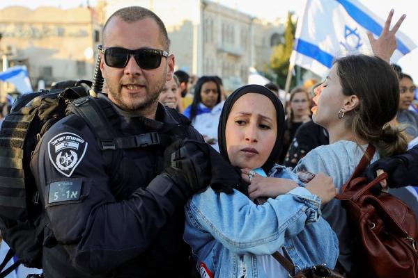 Polisi Israel menyingkirkan warga Palestina dari kawasan yang hendak dilalui para peserta pawai zionis di Yerusalem Timur, Selasa (15/6/2021). (Foto: Reuters)