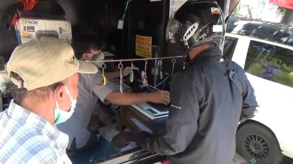 Dadan Hermawan melayani warga yang hendak mencetak kartu sertifikat vaksinasi Covid-19. (Foto: iNews/Yuwono Wahyu)