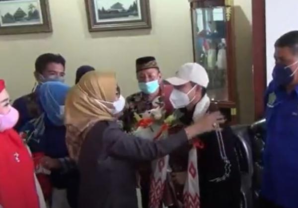 Pebulu tangkis ganda putri Indonesia peraih medali emas Olimpiade Tokyo 2020, Apriyani Rahayu mendapat kalungan bungan dan kain tenun khas Sultra setibanya di Bandara Haluoleo Kota Kendari, Jumat (27/8/2021). (Foto: MNC Portal/Febriyono Tamenk)