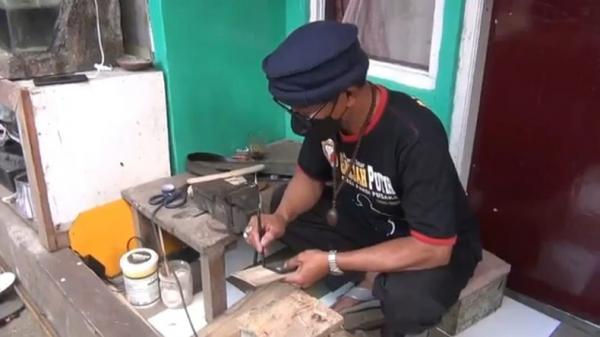 Taryana sedang mengerjakan pesanan cashing HP berbentuk golok. (Foto: iNews/YUWONO WAHYU)