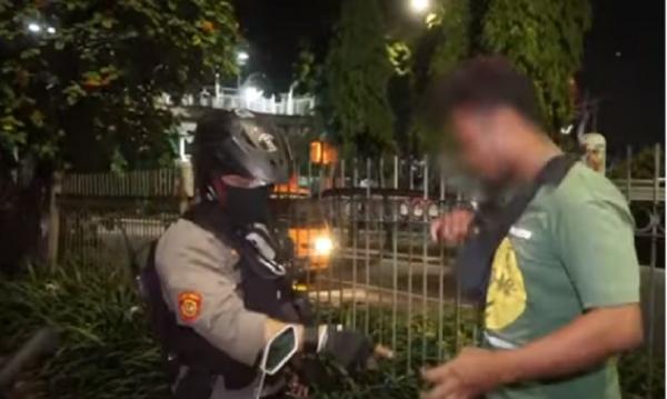 Aipda Monang Parlindungan Ambarita memeriksa pemuda yang berkeliaran di jalan (Foto : Tangkapan Layar Youtube)