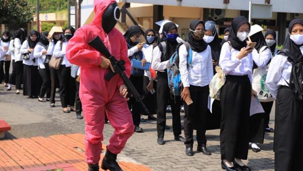 Para peserta tes CPNS Kemenkumham Jawa Timur (Jatim) dikawal dan diawasi oleh panitia yang berdandan ala pink soldier dalam film seri Squid Game.  (Foto: Kemenkumham Jatim)