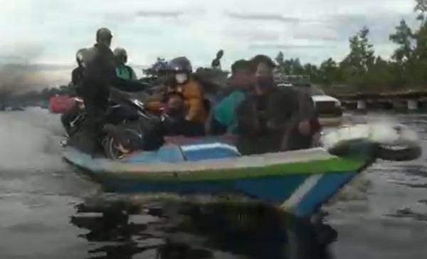 Sejumlah pengendara motor harus menyewa perahu untuk melintasi Jalan Trans Kalimantan Kahayan Tengah yang tergenang banjir. (Foto: iNews TV/Ade Sata)