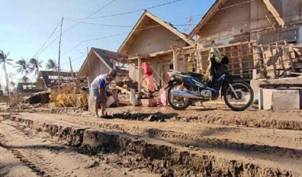 Tukiran membersihkan rumahnya yang tertimbun abu vulkanis Gunung Semeru, Jumat (10/12/2021). (Foto: MPI/Tritus Julan).