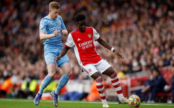 Winger Arsenal, Bukayo Saka vs Kevin De Bruyne Winger Arsenal, Bukayo Saka (kanan) ditempel ketat playmaker Manchester City, Kevin De Bruyne dalam laga Liga Inggris 2021/2022 di Stadion Emirates, London, Sabtu (1/1/2022). (Foto: REUTERS/John Sibley)