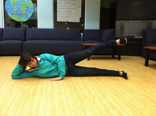 Lying leg raises diperagakan seorang wanita di dalam ruangan. (Foto: Wikimedia Commons)