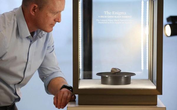 Berlian Hitam The Enigma 2 Reu Kurator ilmu mineral di Museum Sejarah Alam Los Angeles, Aaron Celestian, mengamati berlian The Enigma sebelum dilelang oleh Sotheby's di Beverly Hills, California, AS, Rabu (26/1/2022). (Foto: Reuters)