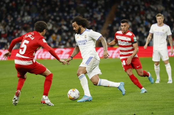 Bek Real Madrid, Marcelo berusaha melewati hadangan pemain Granada dalam laga Liga Spanyol 2021/2022 di Stadion Santiago Bernabeu, Senin (7/2/2022). (Foto: REUTERS/Juan Medina)